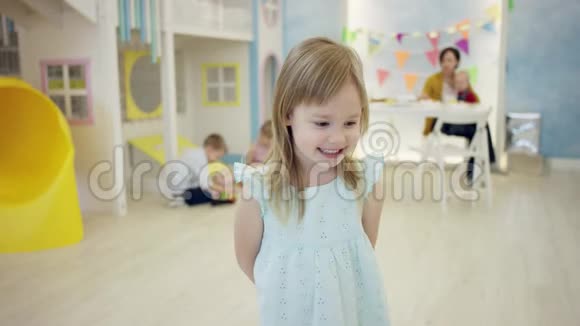 快乐的小女孩正在房间里与其他孩子和成年女人在镜头前微笑和摆姿势视频的预览图