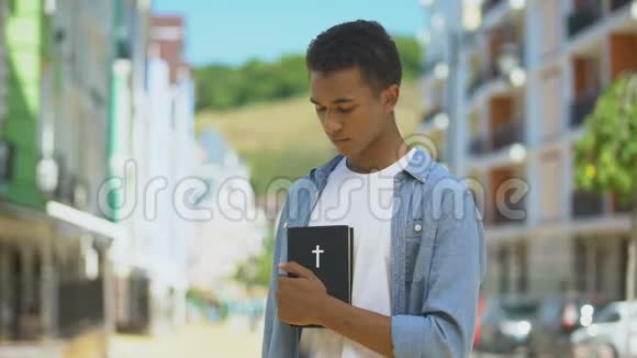 忠诚的混血少年男性看着手中的圣经宗教和上帝视频的预览图