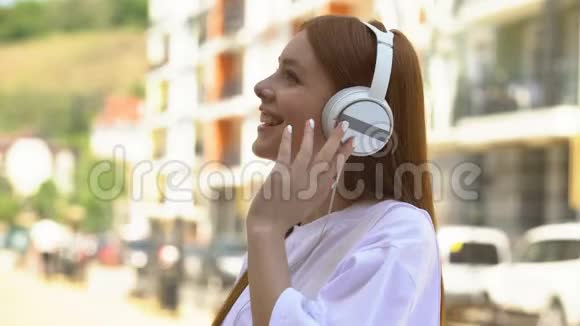 戴着耳机听着城里街头最喜欢的音乐的漂亮少女视频的预览图
