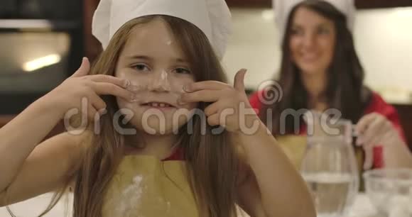 快乐的白种人女孩用面粉和舞蹈在脸上画线条的肖像她年轻的母亲站在视频的预览图