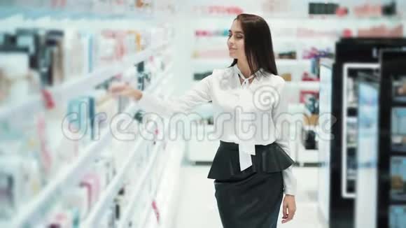 快乐的女人在化妆品店里选择香水在测试器上喷洒嗅嗅视频的预览图