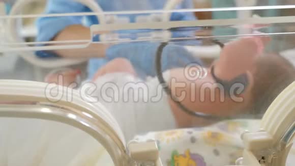 在婴儿培养箱中为婴儿设置医疗传感器的医生手的特写镜头强化治疗附加医生视频的预览图