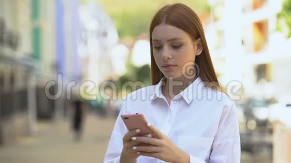 年轻红发女性在智能手机上滚动社交网络被新闻震惊视频的预览图