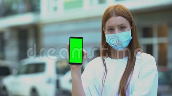 戴病面具的女孩拿着绿色屏幕电话在线预约医生视频的预览图