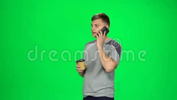 年轻的男性走在电话里喝着咖啡色度键视频的预览图