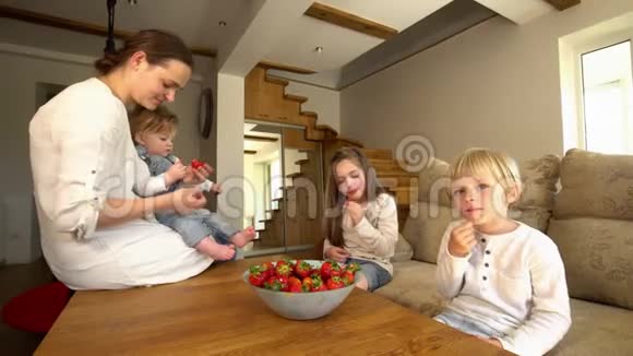 快乐的母亲有两个儿子和女儿吃成熟的红色草莓视频的预览图