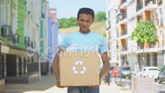 快乐混血少年环保志愿者拿着有回收标志的纸盒视频的预览图