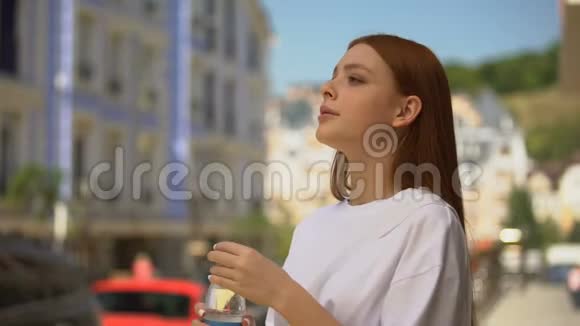 美丽健康的女性在城市街道上喝新鲜的静水茶点视频的预览图