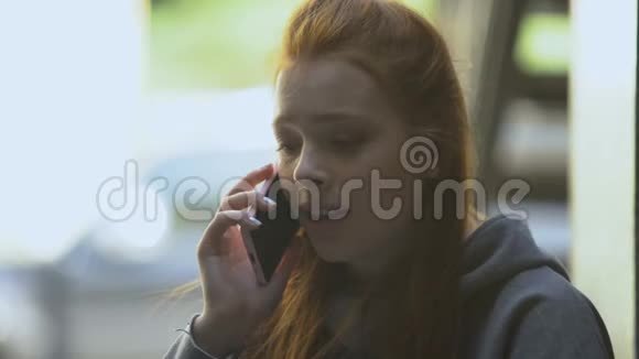 红发年轻女性在智能手机上哭泣和交谈需要帮助和支持视频的预览图