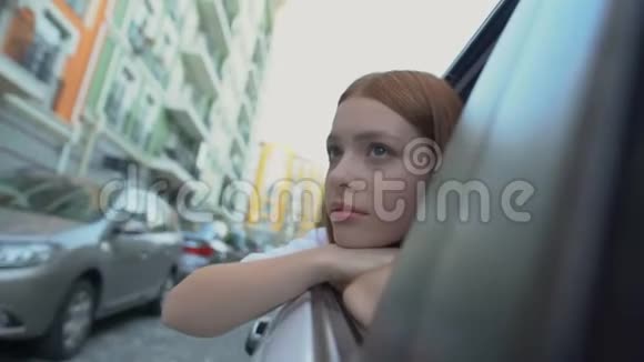伤心的女孩告别坐在汽车后座上的家乡重新安置视频的预览图
