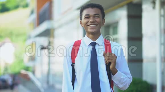 带着背包在摄像机上摆姿势微笑的非裔美国男学生教育视频的预览图