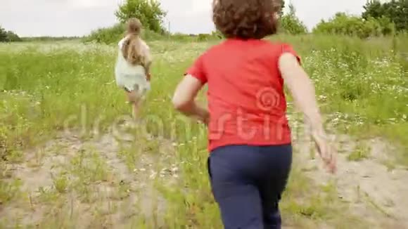 小男孩跑到绿野上的女孩孩子们在户外玩耍视频的预览图