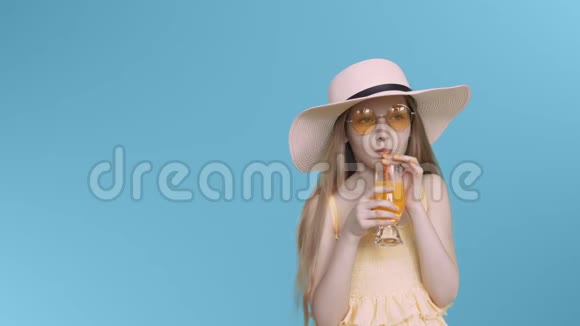 年轻的少女戴着黄色眼镜戴着帽子在蓝色屏幕上喝鸡尾酒视频的预览图