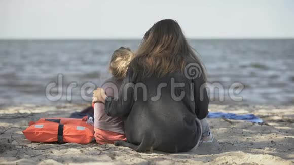 母亲和女儿坐在海边的救生衣附近幸免于难视频的预览图