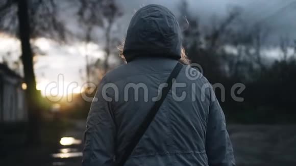 一个穿着兜帽夹克的女孩迎着日落向前走回放缓慢视频的预览图