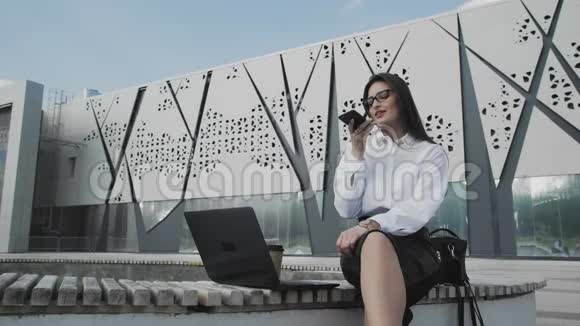 女人正拿着笔记本坐在公园里录制语音留言视频的预览图