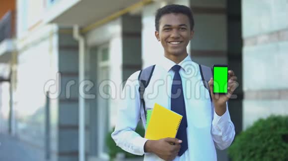 性格开朗的混血男学生课本显示绿色屏幕手机视频的预览图