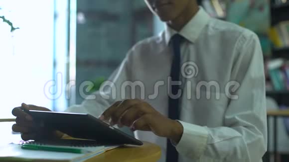 穿着校服在平板电脑上上网做作业的年轻男性视频的预览图