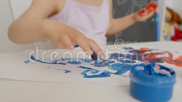 一个小女孩的手特写用鲜艳的颜色在纸上画画用手指蘸着颜料罐视频的预览图