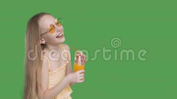 笑的女孩手里拿着橙汁杯在透明的绿色背景上戴黄色眼镜的快乐少女视频的预览图