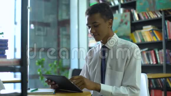 Geek混血男学生在网上做作业在图书馆使用平板电脑视频的预览图