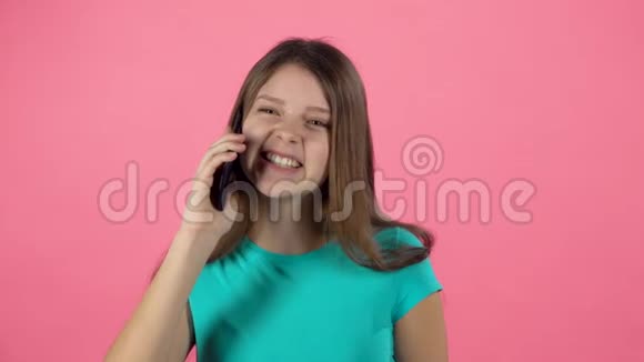 十几岁的女性在画室用手机对着粉红色的背景说话慢动作视频的预览图