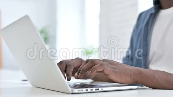 关闭在笔记本电脑上工作的非洲青年男子手视频的预览图