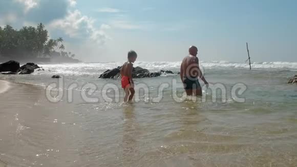 男孩和爸爸在热带度假胜地海洋中休息慢动作视频的预览图