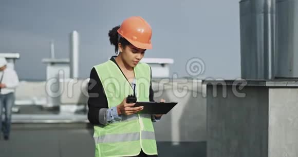 混合皮肤的年轻建筑女士看起来非常专注于她的工作因为她看着她的IPAD她非常惊讶视频的预览图