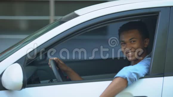 快乐少年把车钥匙给车窗坐在驾驶座上视频的预览图