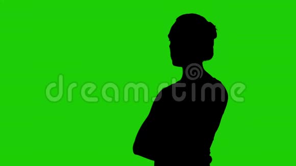 女人她的侧影半转双臂交叉在绿色的背景上视频的预览图