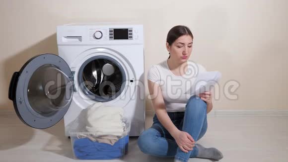 穿牛仔裤的年轻家庭主妇用说明书学习新洗衣机的设置视频的预览图