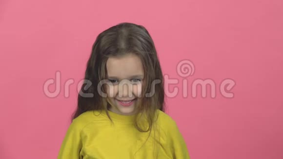 带着微笑的困惑的孩子正在粉红色的背景上拍手慢动作视频的预览图