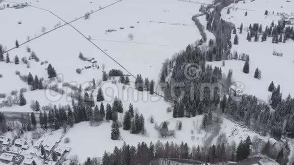从高处俯瞰道路穿过积雪覆盖的田野和树木视频的预览图