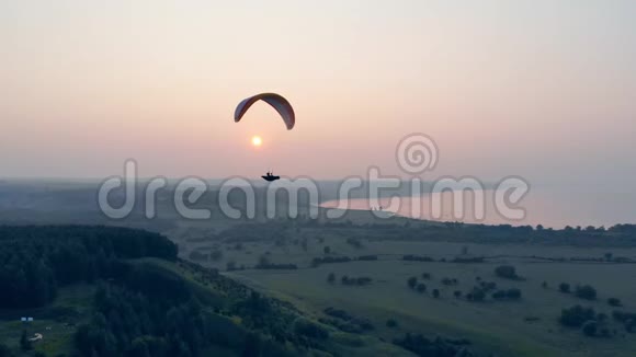 空中滑翔伞帆船正在绿色景观之上漂流降落伞滑翔伞视频的预览图