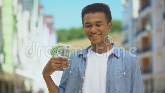 很高兴混合种族的年轻男性展示了一束欧元和微笑第一工资金融视频的预览图