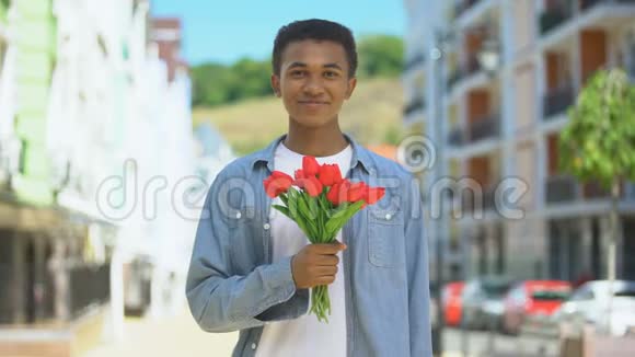 快乐的美国年轻男子捧着郁金香花束在相机礼物上微笑视频的预览图