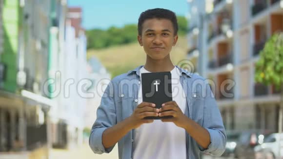快乐的非裔美国男孩在镜头上展示圣经微笑宗教视频的预览图