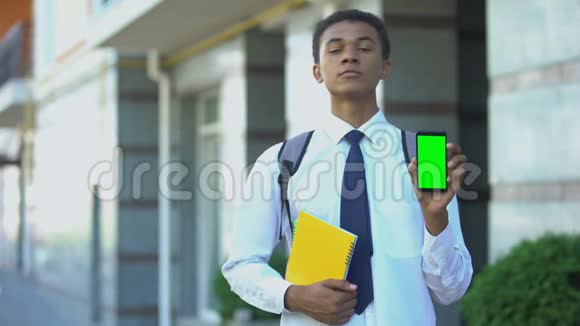 自信的黑人男学生书上显示绿色屏幕智能手机应用程序视频的预览图