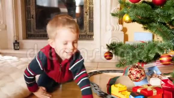 4k视频小笑男在客厅的圣诞树下玩玩具火车和铁路视频的预览图