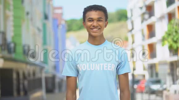 年轻的混血男志愿者双臂交叉在户外的凸轮上微笑帮助视频的预览图