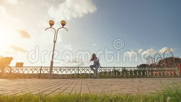 夏天日落时坐在篱笆上的快乐女孩录像在移动录像在移动视频的预览图