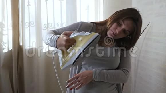 一个年轻的孕妇正试图熨烫但熨斗不起作用家务活视频的预览图