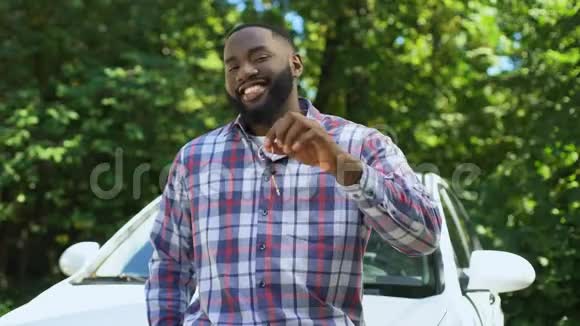 微笑的美国男子展示汽车钥匙倾斜新汽车租赁服务视频的预览图