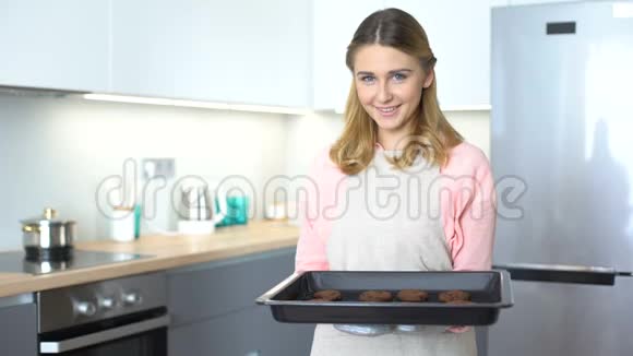 穿着围裙的开朗的家庭主妇拿着烤饼干美味的糕点广告视频的预览图