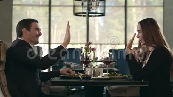 快乐的一对夫妇在餐馆里伸出了第五只手男人和女人碰杯视频的预览图