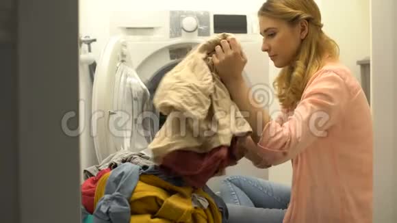 女人把衣服放进洗衣机家庭洗衣服务日常生活视频的预览图