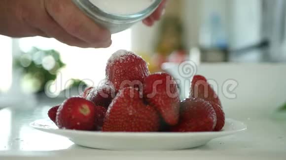 厨房里的男人用新鲜草莓把白色水晶糖撒在碗里视频的预览图