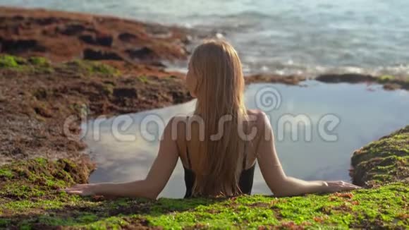 年轻的女游客在巴厘岛的潘泰特加尔旺吉海滩的一个天然的带海水的小池塘里放松视频的预览图