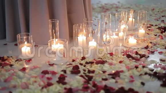 白色燃烧的蜡烛在玻璃瓶中玫瑰花瓣躺在冰上视频的预览图